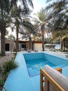 uma piscina com palmeiras num quintal em منتجع ريتام em Al Ahsa