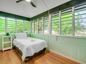 a bedroom with green walls and a bed and windows at Historic Character-filled Jade Cottage in Coalfalls