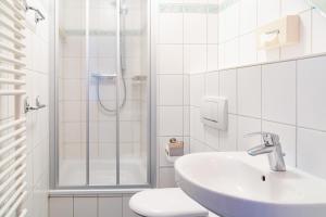 La salle de bains blanche est pourvue d'un lavabo et d'une douche. dans l'établissement Hanse Appartement II Warnemünde, à Warnemünde