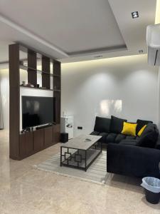 uma sala de estar com um sofá preto e uma televisão em منتجع ريتام em Al Ahsa