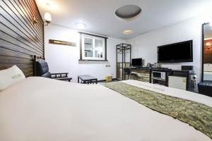 a hotel room with a large bed and a flat screen tv at Cheonan Business Hotel in Cheonan