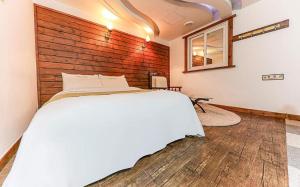 a bedroom with a white bed and a wooden wall at Cheonan Business Hotel in Cheonan