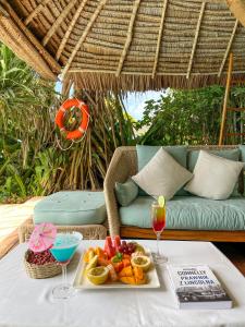 a table with a tray of fruit and a drink at Tulia Zanzibar Unique Beach Resort in Pongwe