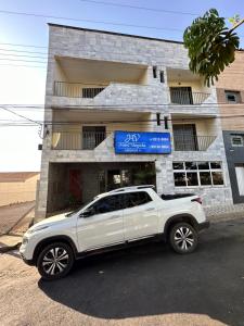 a white suv parked in front of a building at HOTEL VARGINHA II in Varginha