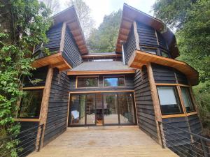 una casa con una gran puerta de cristal en la parte delantera en Mágica Casa Enclavada en el Corazón del Bosque, en Reserva Biológica Huilo Huilo