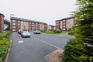 ein Parkplatz mit Autos vor Backsteingebäuden in der Unterkunft SuperbSleep Apartments in Glasgow