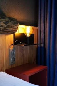 a room with a bed with a lamp and a table at Le Motel du Gaschney in Muhlbach-sur-Munster
