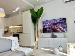 uma sala de estar com um sofá e uma televisão na parede em La Colombe de Sidi Bou Saïd em Dar Salah Bey