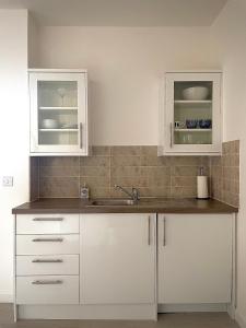 una cocina con armarios blancos y fregadero en Central 2-bedroom apartment, Montrose, en Montrose