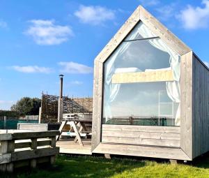 a small shed with a window on a deck at Lushna 3 Petite at Lee Wick Farm Cottages & Glamping in Clacton-on-Sea