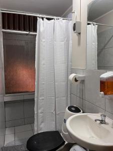a bathroom with a white shower curtain and a toilet at Hostel Pepe Lima in Lima
