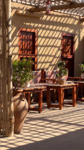 een patio met 2 houten tafels en potplanten bij Liwa Nights ليالي ليوا in Liwa