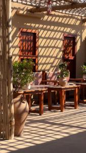 a patio with two wooden tables and potted plants at Liwa Nights ليالي ليوا in Liwa