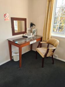 einen Schreibtisch mit einem Spiegel und einem Stuhl in einem Zimmer in der Unterkunft The Hillmorton Manor Hotel in Rugby
