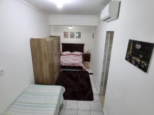 Kitnets em Caraguatatuba في كاراغواتاتوبا: غرفة صغيرة بسريرين في غرفة بها سرير
