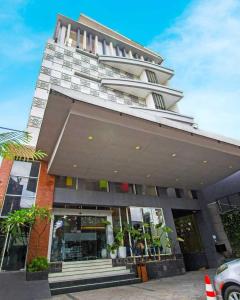 un gran edificio alto con una tienda frente a en Hotel FortunaGrande Seturan Yogyakarta, en Yogyakarta