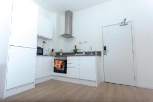 a kitchen with white cabinets and a refrigerator at One Bedroom apartment Serviced apartment Smethwick flat 320 in Birmingham
