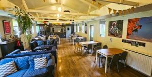 a restaurant with blue couches and tables and tables and chairs at Wooler Youth Hostel and Shepherds Huts in Wooler