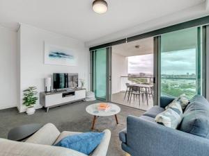 a living room with a blue couch and a table at Spectacular River View Apartment in Brisbane