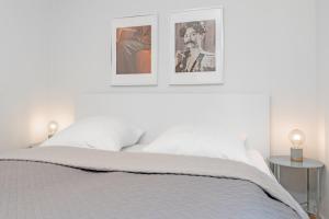 Dormitorio blanco con 2 cuadros encima de una cama en Haus "Kehrwieder" Kap Arkona, en Grömitz