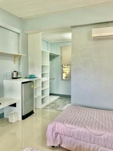 um quarto com uma cama roxa e uma cozinha em PJ PLACE em Chiang Rai