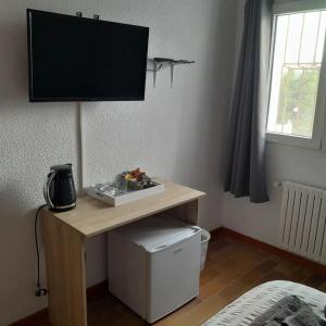 Zimmer mit einem Schreibtisch und einem TV an der Wand in der Unterkunft DJM Palms B&B - No es una casa privada in Ayora