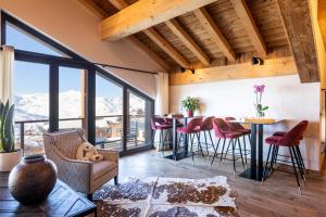 a living room with a table and chairs and windows at Chalet Carte Blanche Cullinan in Val Thorens