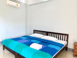 Schlafzimmer mit einem Bett mit blauer Tagesdecke in der Unterkunft PJ PLACE in Chiang Rai