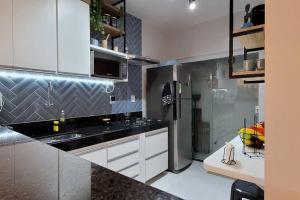 a kitchen with white cabinets and a black counter top at Apartamento único e aconchegante! in Cabo Frio