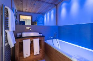 Baño azul con bañera y lavamanos en Chalet Carte Blanche Orlov en Val Thorens