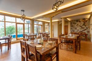 a restaurant with wooden tables and chairs and windows at Sand Dunes Retreat in Leh