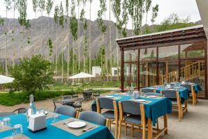 a restaurant with blue tables and chairs with mountains in the background at Sand Dunes Retreat in Leh