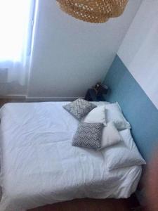 um quarto com uma cama branca com almofadas em A 300 mètres de Paris 13, superbe deux pièces neuf em Ivry-sur-Seine