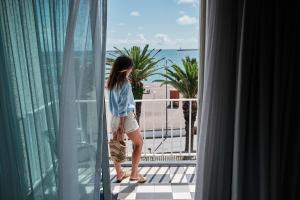 a woman standing on a balcony looking out of a window at Hotel Varandas do Atlântico by RIDAN Hotels in Praia da Vitória