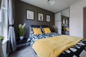 a bedroom with a king sized bed with yellow pillows at ComfySleep Apartments in Glasgow