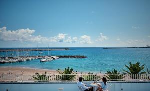 two people sitting at a table looking at the ocean at Hotel Varandas do Atlântico by RIDAN Hotels in Praia da Vitória