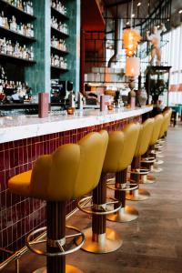 een rij gele barkrukken in een restaurant bij INNSiDE by Meliá Amsterdam in Amsterdam