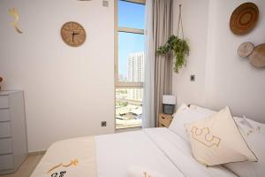 a bedroom with a white bed with a clock on the wall at Luminous 1BR Apartment Al reem in Abu Dhabi