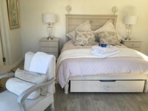 a white bedroom with a bed and a chair at Sage in Montagu +43 photos