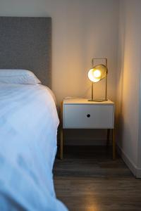 a lamp on a night stand next to a bed at Le 10-GregIMMO-Appart'Hôtel in Belfort