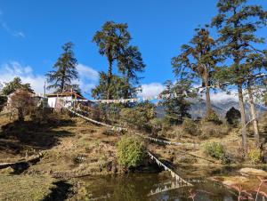 a bridge over a river with trees on a hill at Wake In Himalayas in Pelling
