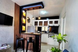 a kitchen with white cabinets and a bar with stools at Apartamento acogedor Ashmi in Santiago de los Caballeros