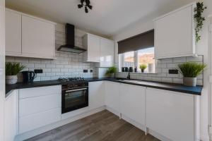 a kitchen with white cabinets and black counter tops at Emirates ApartHOUSE in Glasgow