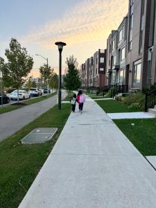 a woman and child walking down a sidewalk at Toronto Downtown Midtown North York Newly Built Modern Bright Room in Toronto