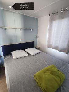 a bedroom with a bed with two pillows and a window at Mobil-home cosy 166 in Narbonne