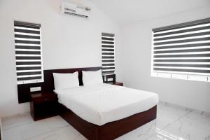 a bedroom with a white bed and two windows at Rockdale Resort in Nilambūr