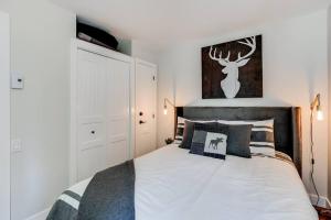 a bedroom with a large bed with white walls at Le Petit Condo B - Ski In/ Ski Out Mont-Tremblant in Mont-Tremblant