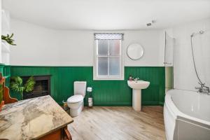 a green bathroom with a tub and a toilet and a sink at The Bristol Harbourside Apartments - Sleeps 16 in Bristol