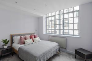 a bedroom with a bed with pink pillows and a window at Law & Order - Farringdon - by Frankie Says in London