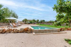 a swimming pool in a yard with two chairs and an umbrella at Cal Tio 1 Agroturismo YourHouse in Costitx